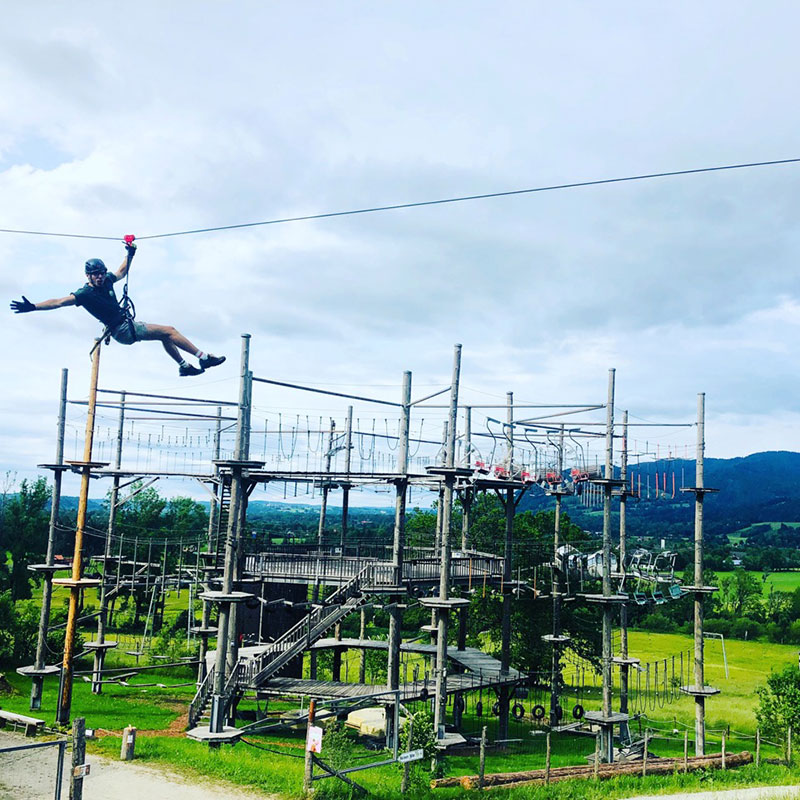 Hochseilgarten mit Flying Fox Fahrer im Vordergrund