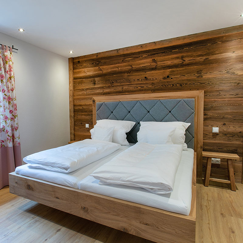 Apartment_Isarflimmern_Schlafzimmer_Bett Doppelbett vor Altholzwand mit Fenster